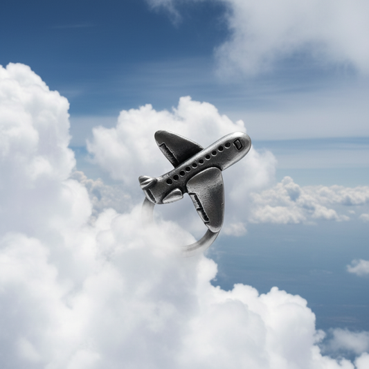 Metallic airplane charm against a blue sky with clouds