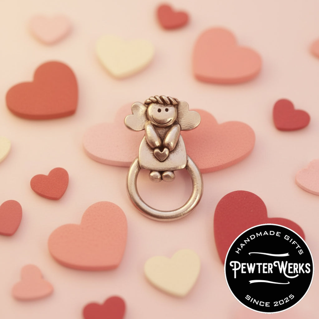 A Pewter 'Angel of Love' Eyeglass Holder on display with a multiple heart background. PewterWerks logo visible.