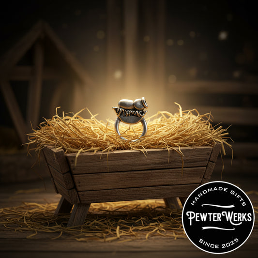 Pewter 'Baby Jesus' Eyeglass Holder glowing in a manger. PewterWerks logo visible.