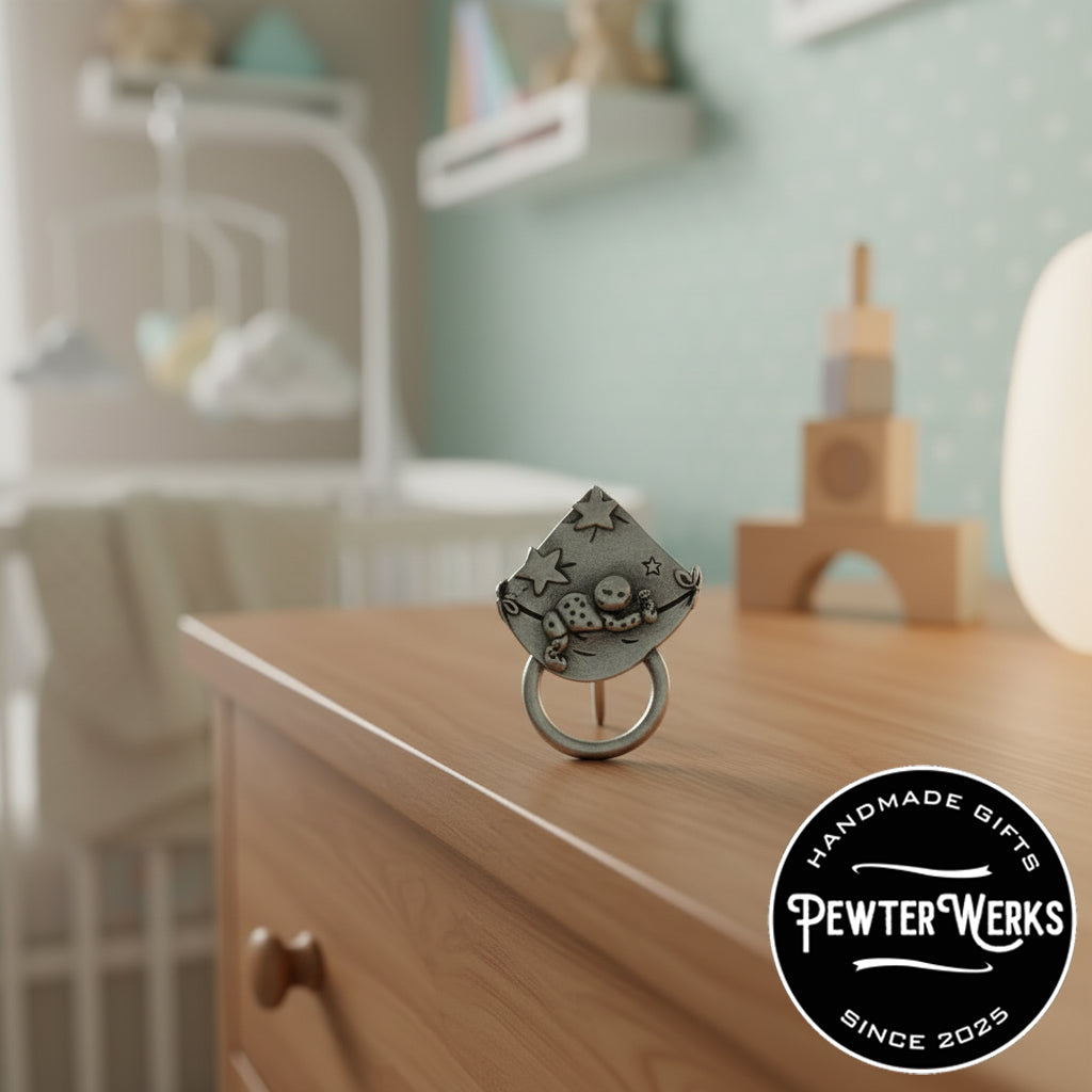 A 'Baby on a Blanket' Eyeglass Holder sitting on the dresser in a baby's room. PewterWerks logo visible.