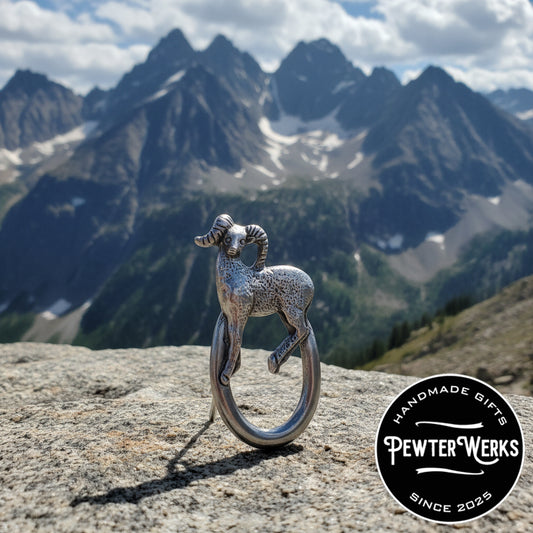 A Pewter 'Big Horn' Eyeglass Holder standing on a rock in the mountains. PewterWerks logo visible.