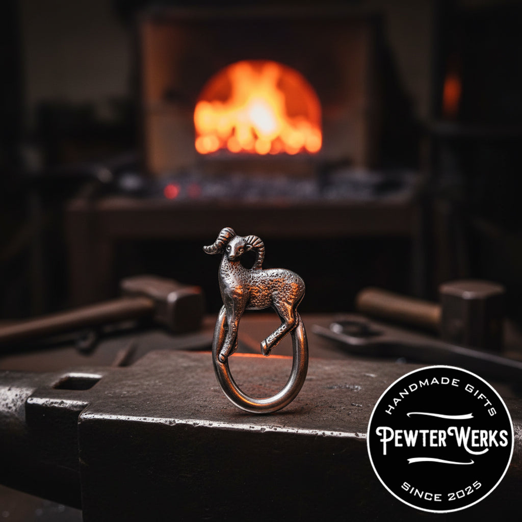 A Pewter 'Big Horn' Eyeglass Holder on an anvil in a foundry. PewterWerks logo visible.