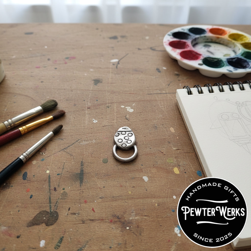 A pewter 'Cartoon Ladybug' eyeglass holder in an artist's just freshly painted. PewterWerks logo visible.