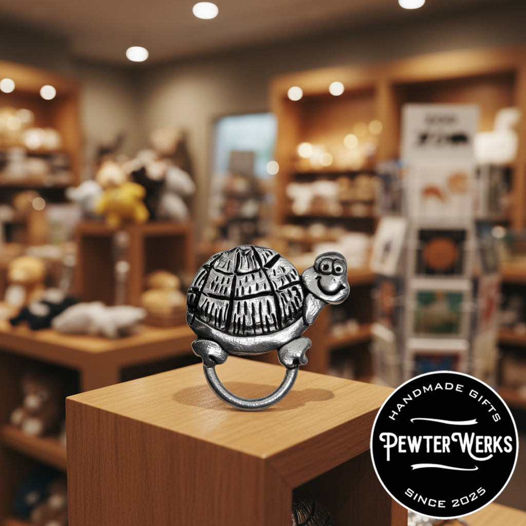 A pewter 'Cartoon Turtle' eyeglass holder on display in a gift shop. PewterWerks logo is visible.