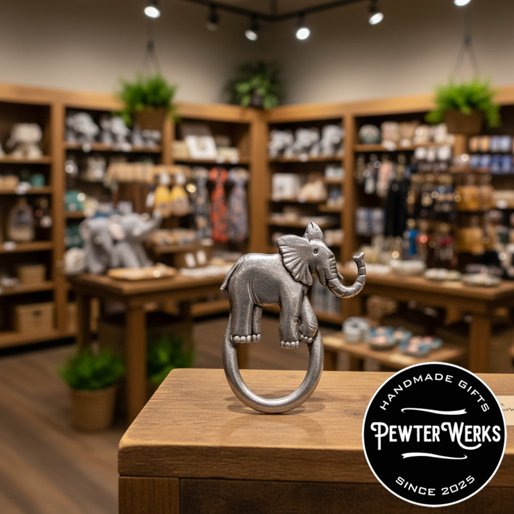 A pewter elephant eyeglass holder on display in a gift shop. PewterWerks logo visible.
