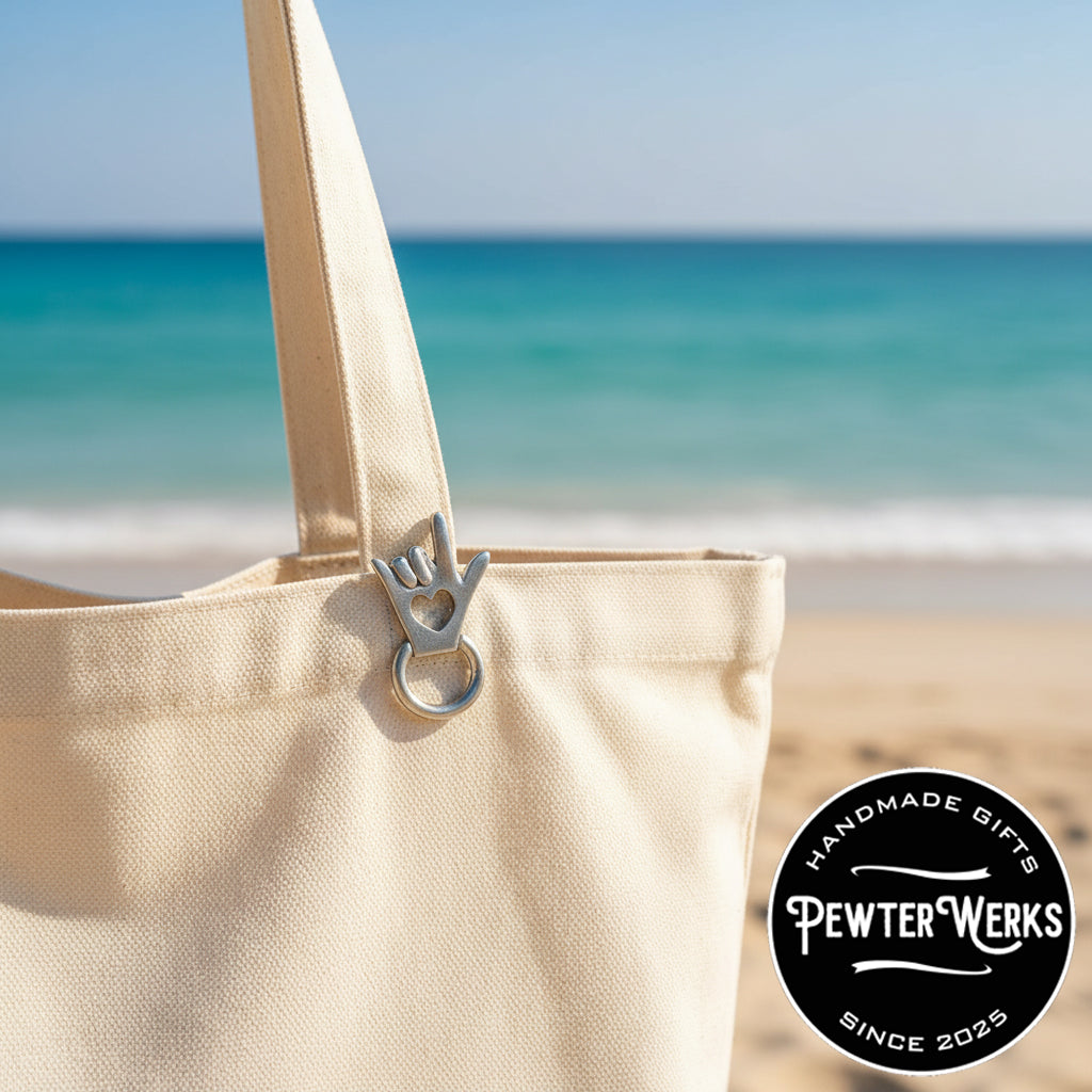 And 'I Love You' Eyeglass Holder pinned to a beach bag at the ocean. PewterWerks logo visible.